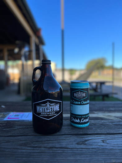 A picture of a 32 oz. Whitestone Brewery Crowler and a 64 oz. Whitestone Brewery Growler bottle sitting in a field of bluebonnet flowers in the Texas Spring. 